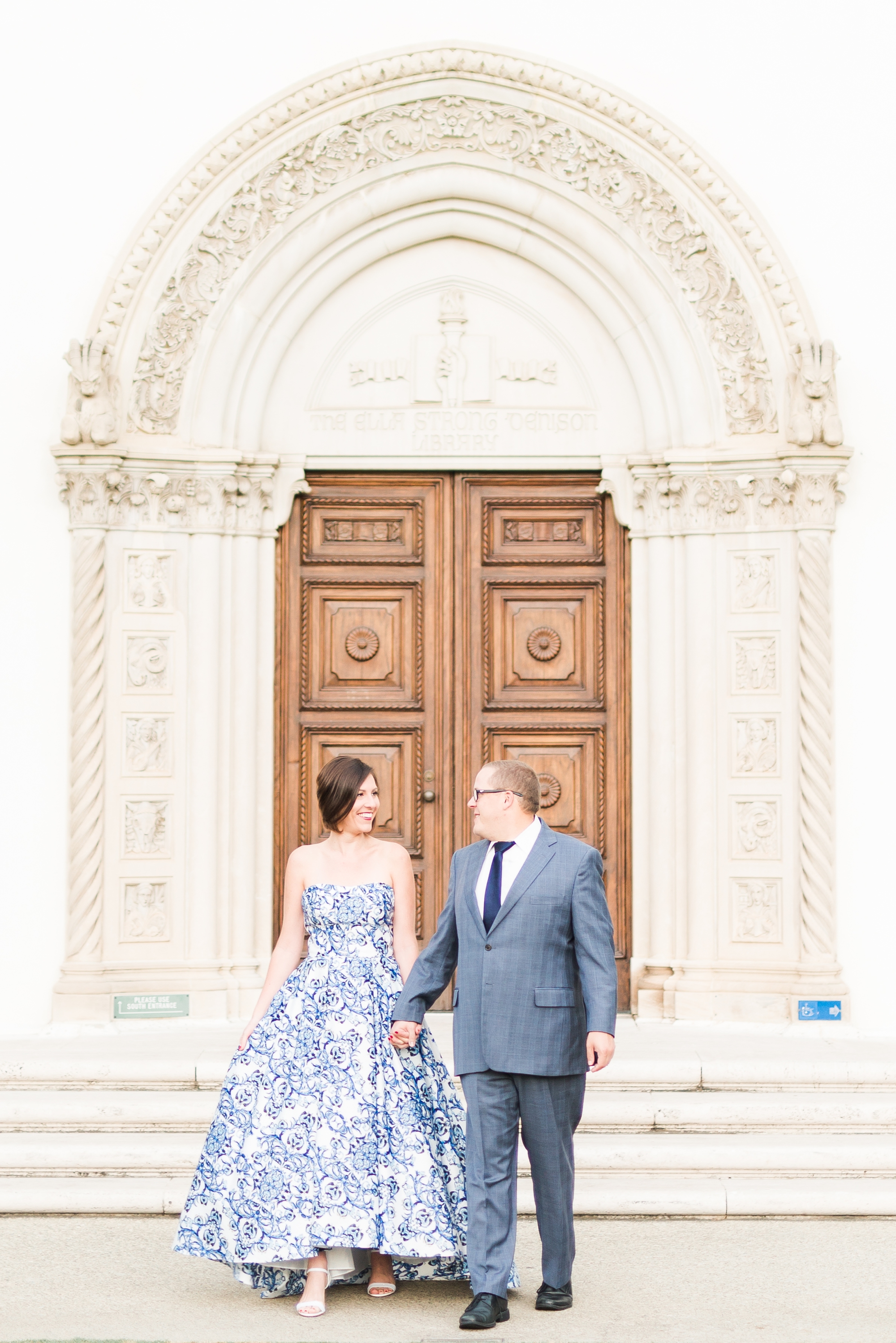 Couples pose in front of large doors with beautiful architecture